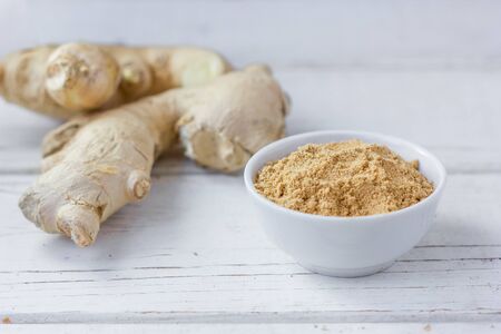 Grounded ginger and ginger root on white wooden surface.の写真素材