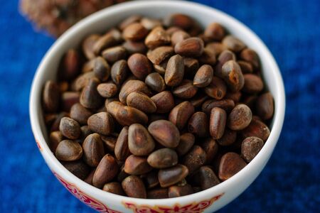 Fresh and ripe pine or cedar nuts in a bowl over blue backgroundの写真素材