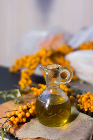 Sea buckthorn oil on bottle, surrounded by seabuckthorn berries.の写真素材