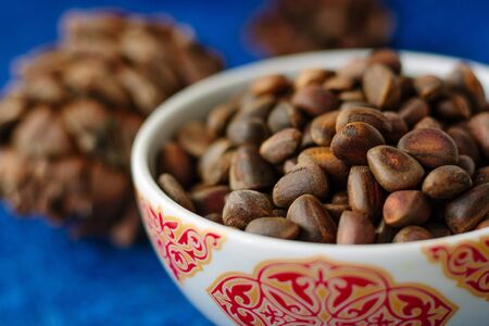 Fresh and ripe pine or cedar nuts in a bowl over blue background.の写真素材
