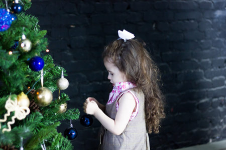 Little kid girl decorating christmas tree for new year celebration.