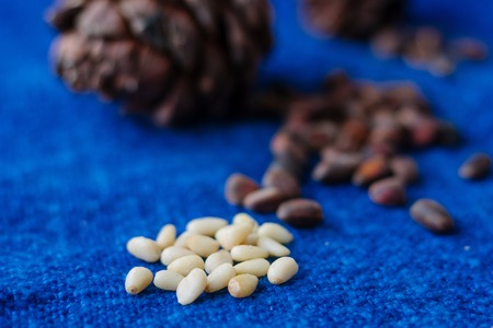 peeled cedar or pine nuts with pine cone on blue surface.の写真素材
