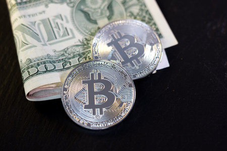 Bitcoin coin and one dollar on black background.