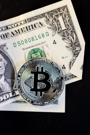 Bitcoin coin and one dollar on black background.