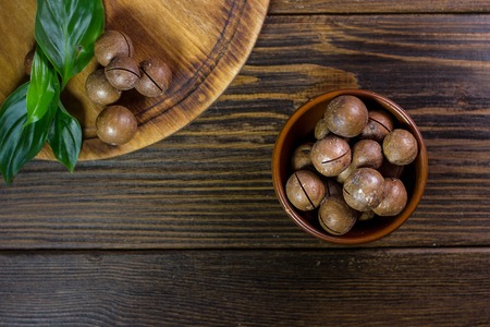 Top view of macadamia nuts in brown ceramic bowl on wooden table.の写真素材