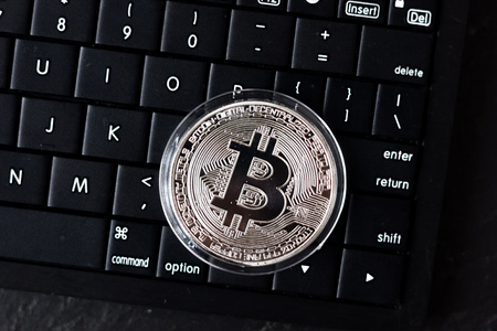 Silver bitcoin coin on black PC keyboardの写真素材