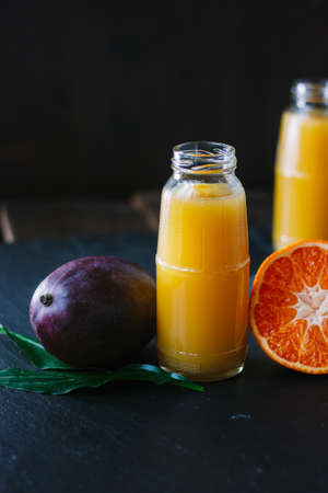 Glass bottles filled by fresh detox mango and orange smoothieの写真素材