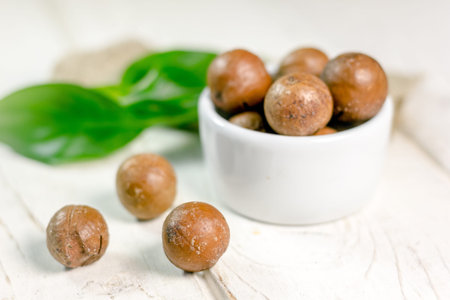 Nice macadamia nuts on white wooden table.
