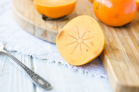 Half of persimmon fruit on wooden board.の写真素材