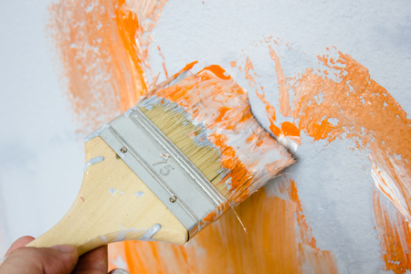 Brush with orange and white paint as renovation and creationの写真素材