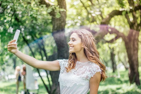 Beautiful girl making selfie at parkの写真素材