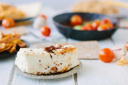 Big piece of tofu - vegan cheese, roasted. With vegetables and other foodの写真素材