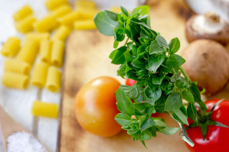 Green basil leaves on kitchen board with vegetablesの写真素材