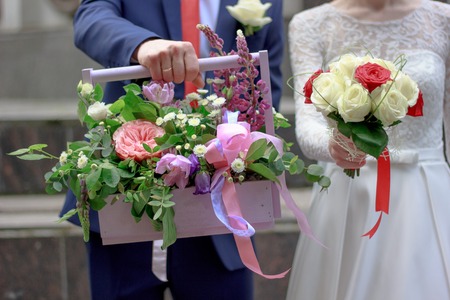 Hands of young couple holding a basket with flowersの写真素材