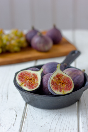 Frying pan with fresh figs inside on a white wooden tableの写真素材