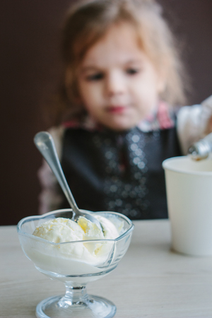 Ice cream on table and little girl on backgroundの写真素材