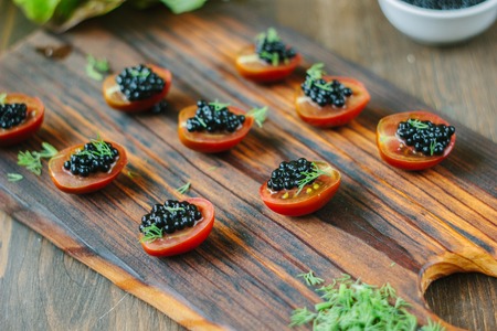 Small appetizers with cherry tomatoes and black caviarの写真素材