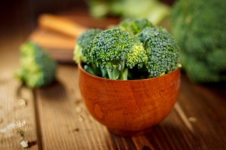 Broccoli crowns in a wooden bowl over tableの写真素材