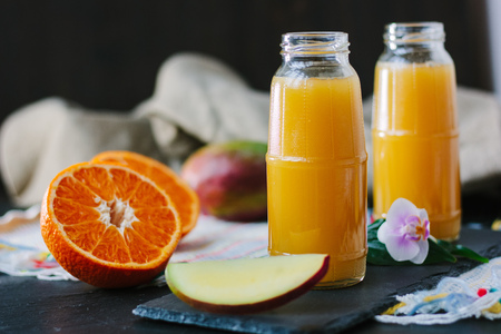 Mango and orange smoothie in transparent bottleの写真素材