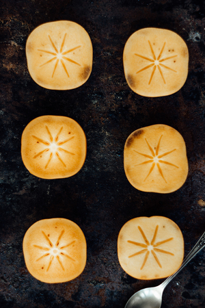 Halves of persimmon fruit on black metal surfaceの写真素材