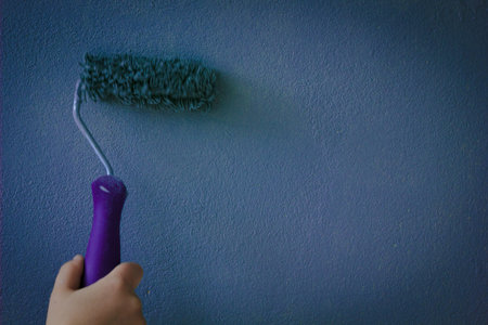 Paint roller over the wall colored by deep blue paintの写真素材