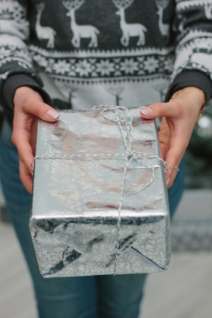 Girl giving a christmas gift in a silver box to you - christmas and new year concept.の写真素材