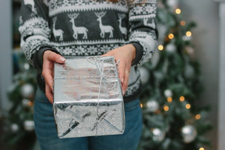Girl giving a christmas gift in a silver box to you - christmas and new year concept.の写真素材