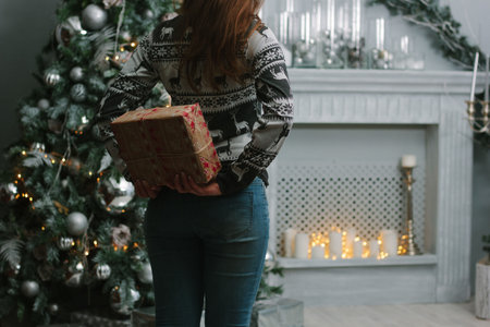 Girl making christmas surprise - holding gift behind a back - christmas and new year concept.