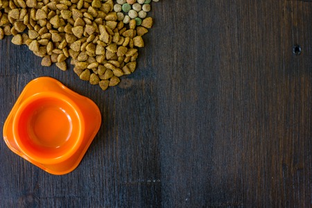 Small orange bowl for pet food and dry food as backgroundの写真素材