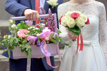 Hands of young couple holding a basket with flowersの写真素材