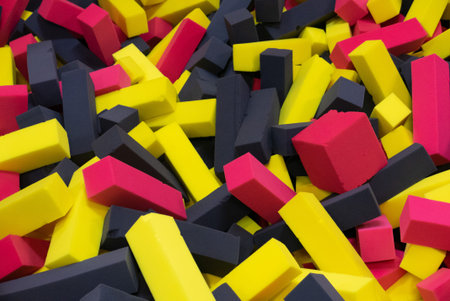Pool in the kid game center filled by yellow red and black cubes.