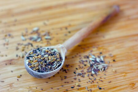 Spice mix inside the wooden spoon on a tableの写真素材