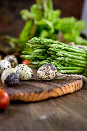 Asparagus and quail eggs on wooden board.の写真素材