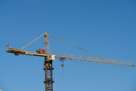 Tower crane on construction site against blue sky.の写真素材