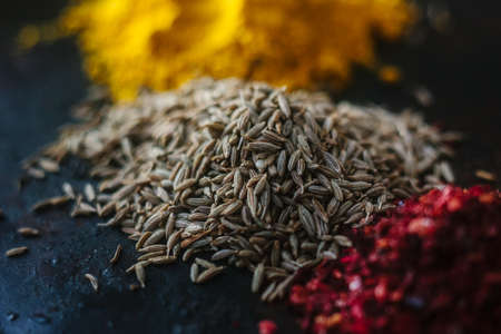 Cumin seeds surrounded by spices over black surface.の写真素材