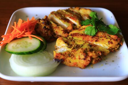 Delicious Grilled chicken served with onion, cucumber and carrots in white plate. Tasty grilled chicken.の写真素材