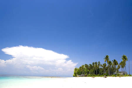 Image of a remote Malaysian tropical island with deep blue skies, crystal clear waters, atap huts and coconut trees.の写真素材