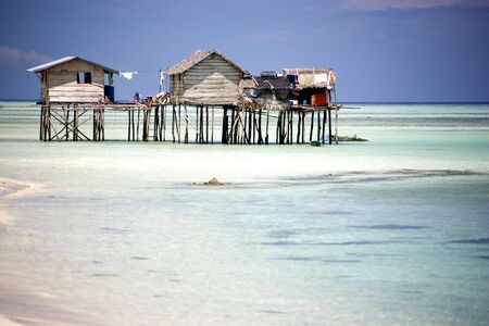 Image of huts on stilts with clear water in the foreground and blue skies in the background.の写真素材