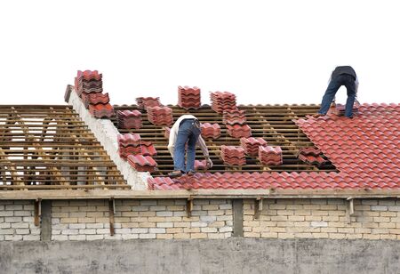 Image of workers laying roof tiles on an house under construction.の写真素材