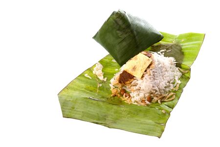 Isolated image of rice cooked in coconut milk and packed in banana leaf, commonly known as Nasi Lemak. This Malaysian delicacy is served with spicy paste, anchovies, groundnuts, cucumber slices, and is usually taken in the morning for breakfast.の写真素材