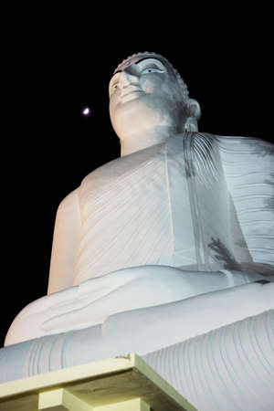 Night image of Bahirawakanda Budha, a giant buddha statue sitting on top of a hill at Kandy, Sri Lanka.の写真素材