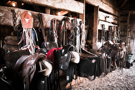 worn saddles and tack in a barn with an aged lookの写真素材