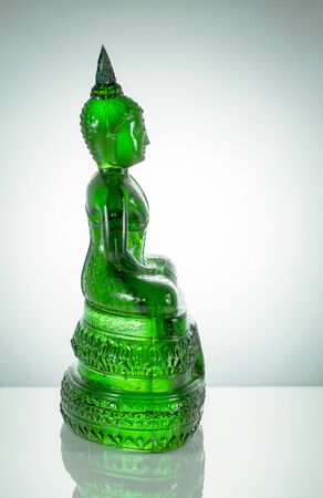 Side view of emerald Buddha statue with reflection on white backgroundの写真素材