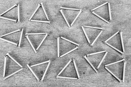 closeup of chrome screws texture background formed as triangle on vintage wooden background in...