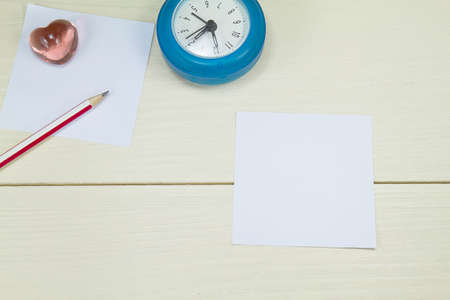 White papers, pencil, alarm clock and pink glass heart shaped on wooden backgroundの写真素材