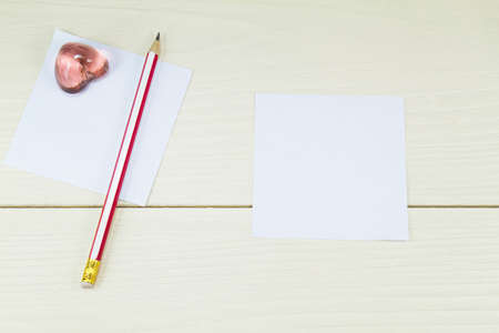 White papers, pencil and pink glass heart shaped on wooden backgroundの写真素材