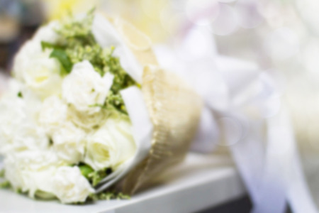 Blurred bouquet of white roses on white table on blurred bokeh backgroundの写真素材