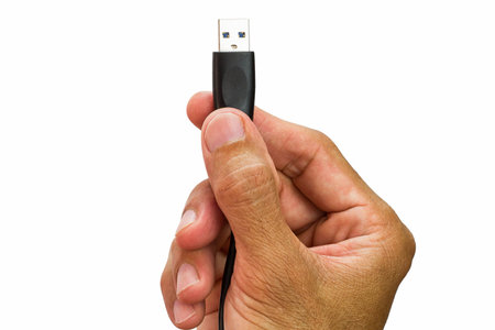 Man's hand holding usb cable on white backgroundの写真素材