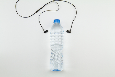 Drinking water bottle with headphone on white bokeh background, sport conceptの写真素材
