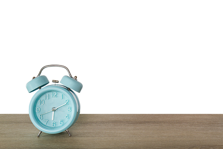 Blue classic alarm clock on vintage wooden desk on white backgroundの写真素材